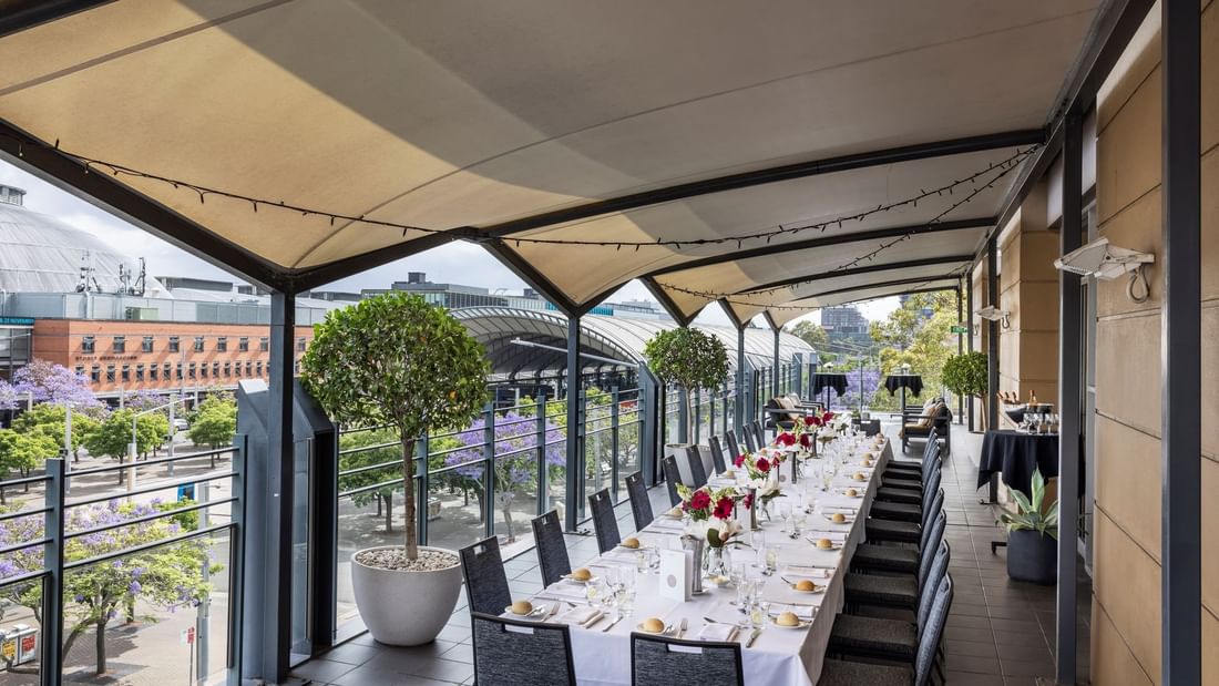 Beautifully set dining table with flowers on Freshwater Balcony, overlooking Accor Stadium at Novotel Sydney Olympic Park