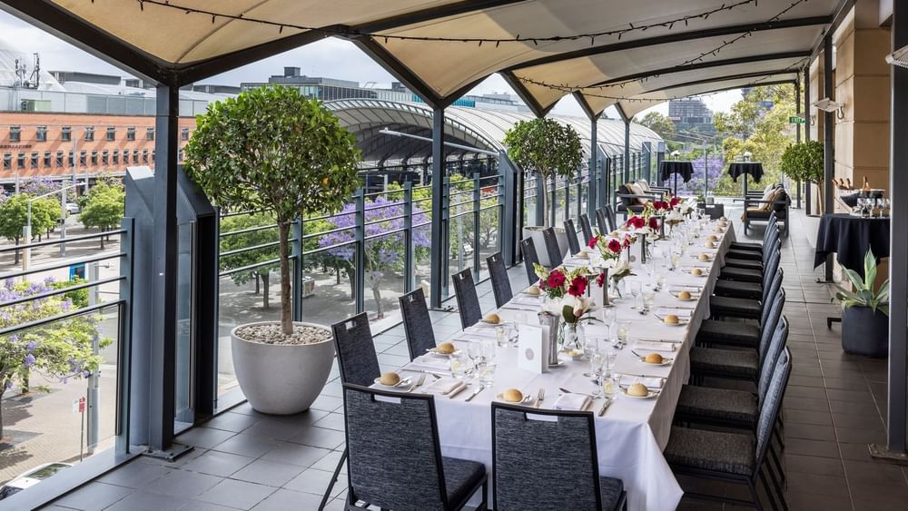Beautifully set dining table with flowers on Freshwater Balcony, overlooking Accor Stadium at Novotel Sydney Olympic Park
