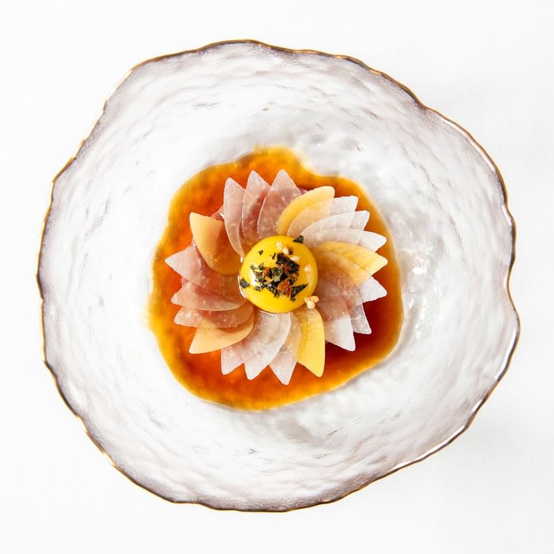 Fine-dining dish, presented like a flower, with a soft egg yolk at its center at Warwick Hotels and Resorts