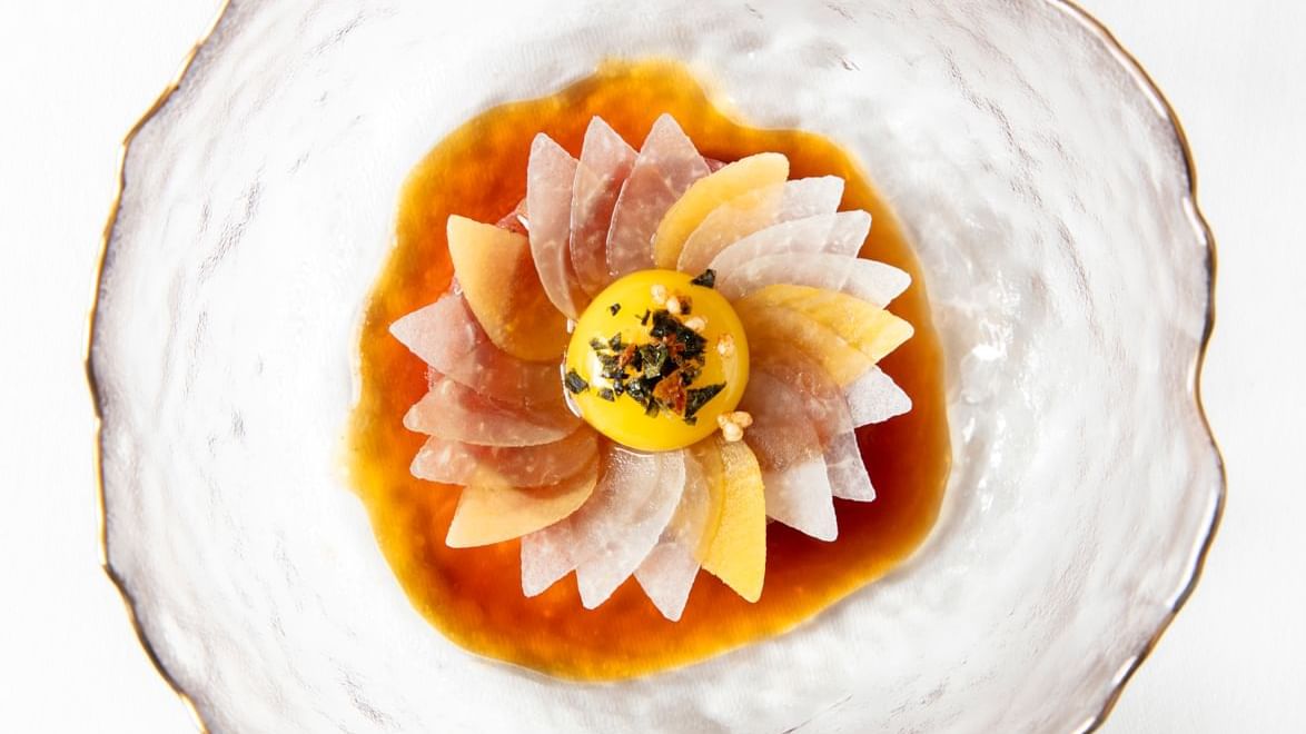 Fine-dining dish, presented like a flower, with a soft egg yolk at its center at Warwick Hotels and Resorts