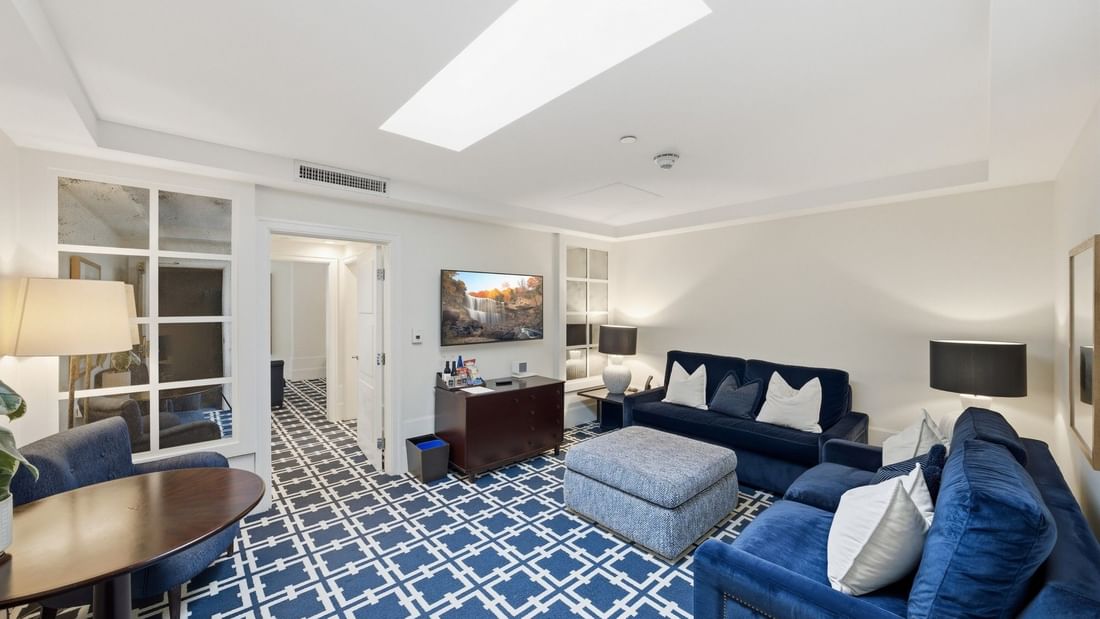 Grand Deluxe Suite living area with blue sofas, patterned carpet, and skylight at el PRADO Hotel in Palo Alto