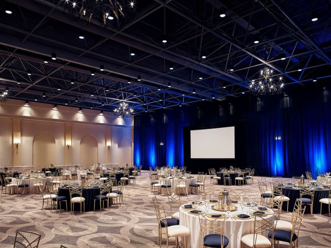 A spacious ballroom at Hacienda del Mar Los Cabos set for a banquet with round tables and dim lighting