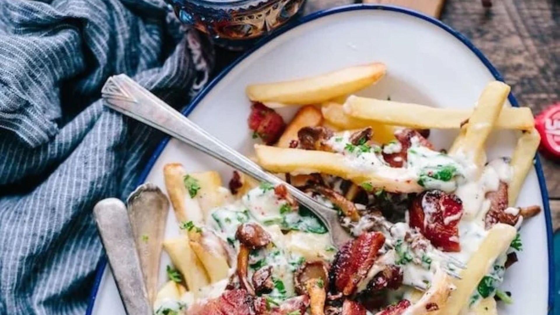 Plate of fries topped with bacon and sauce, with fork and knife, promoting 4 Course Dinner at Valencia Restaurant.
