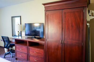 Wooden cupboard with TV and work area in a room by Rosen Inn at Pointe Orlando
