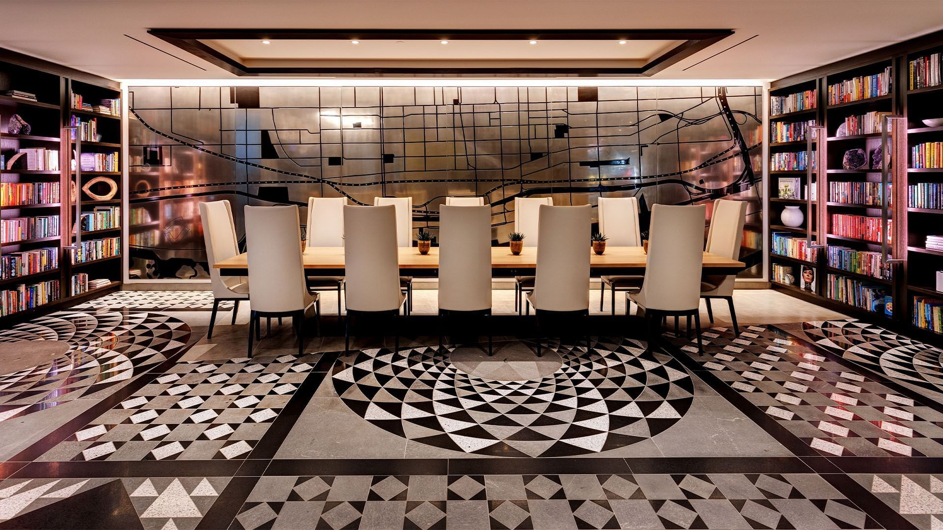 Boardroom at Hotel X Toronto with long conference table surrounded by beige chairs between full wall bookshelf units
