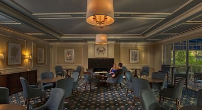 Couple lounging by an indoor fireplace at Trianon Bonita Bay