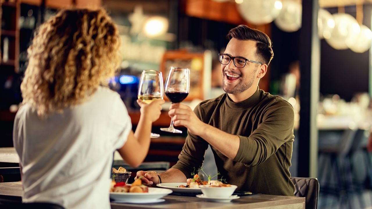 Couple dining and toasting with wine glasses in a restaurant.