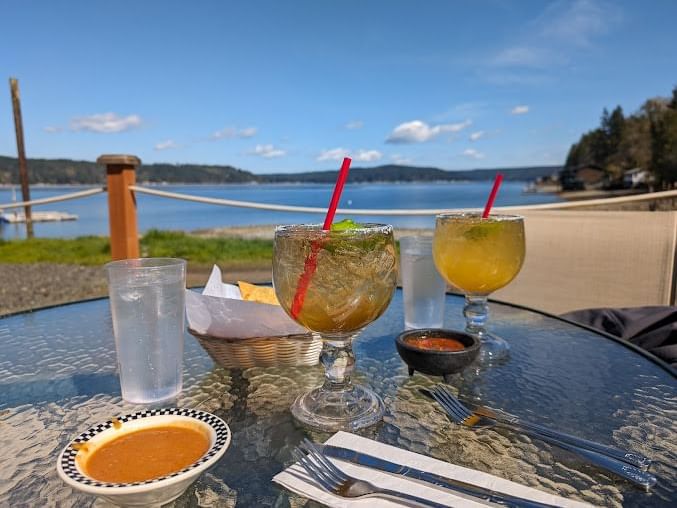 Table with two mojitos and snacks in the Hook & Fork dining area by the lake near Alderbrook Resort & Spa