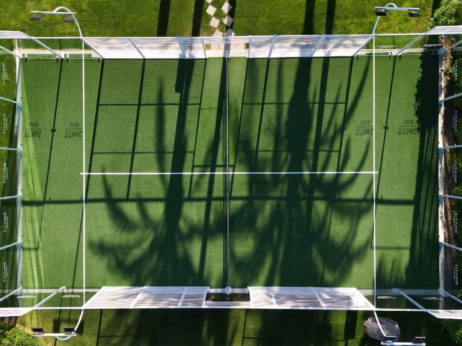 Outdoor padel court view at Titanic Deluxe Lara, with a green surface and glass-framed walls.