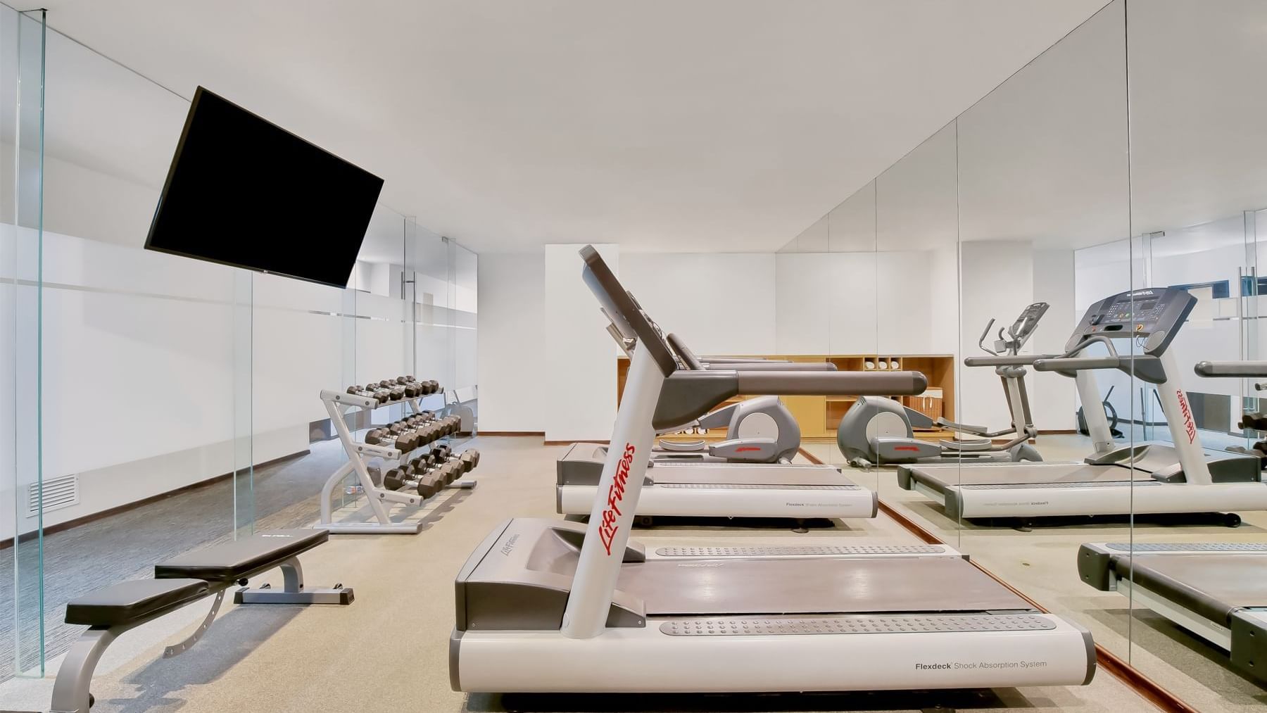 A gym room with tread machines and mirrors at Fiesta Inn