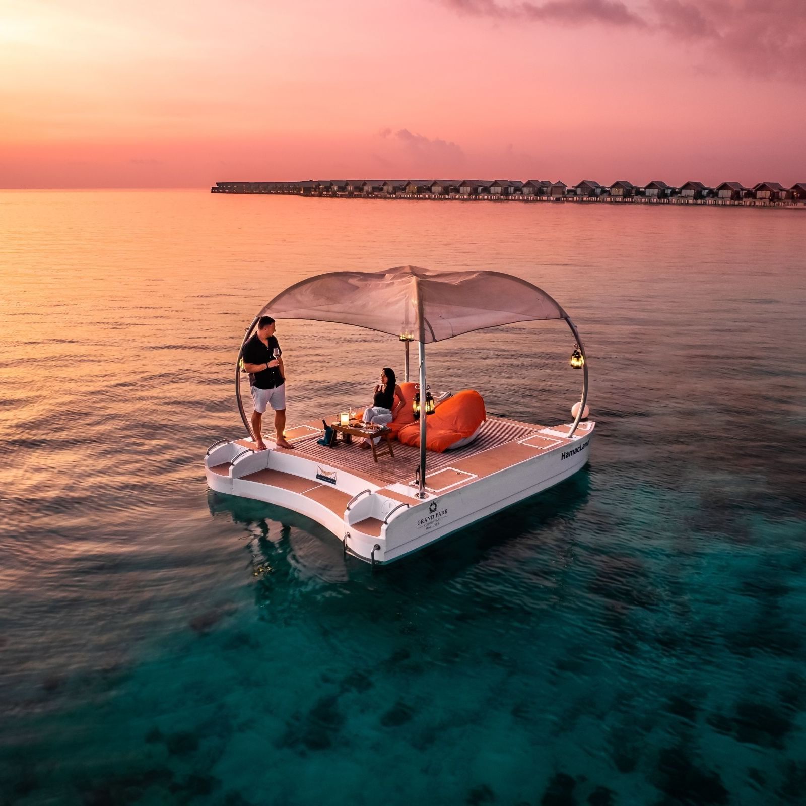 Couple enjoying sunset on a floating deck at Grand Park Kodhipparu Maldives