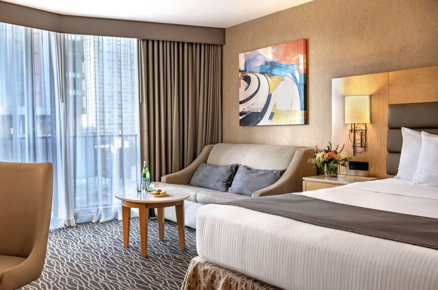 Beige sofa featuring grey pillows by a round coffee table under a painting in Accessible Premier Room at Warwick Seattle