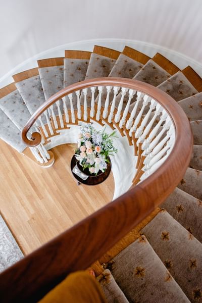 High-angle view of spiral staircase with a flower arrangement on a table at the base in Mt Ada