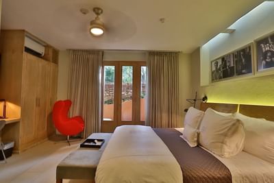 Ottoman and cozy chair by the bed in La Caoba Retreat Suite at Billini Hotel Historic Luxury