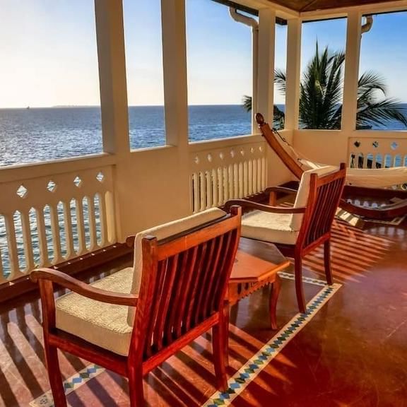 Wooden lounge chairs and hammock on balcony overlooking ocean at Zanzibar Serena Hotel.