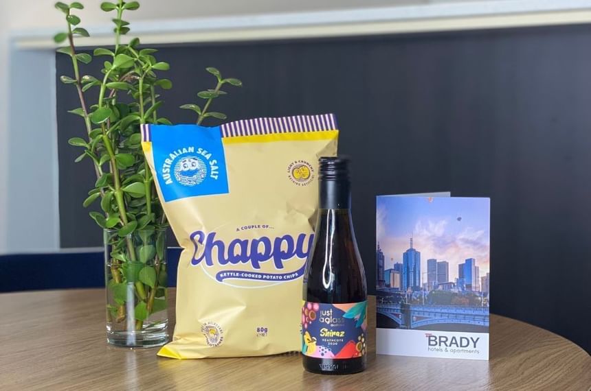 Presenting Chappy chips bag and a Shiraz wine bottle by a hotel handout at Brady Apartment Hotel Hardware Lane