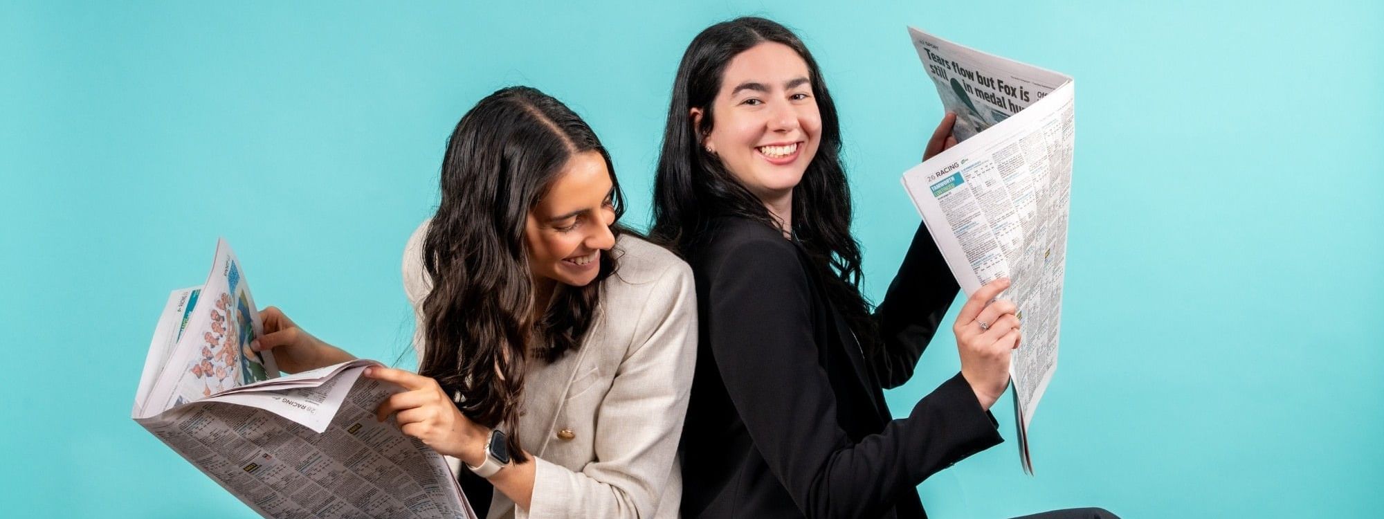 Two women sitting back-to-back reading newspapers at Novotel Sydney Olympic Park
