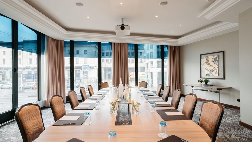 Long wooden table by tan chairs under a projector in Rigi at Warwick Geneva