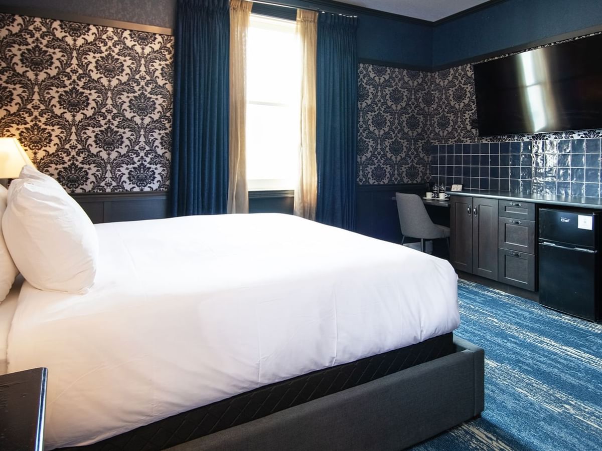 Hotel room with king bed, flat-screen TV, mini fridge, desk, chair, and window