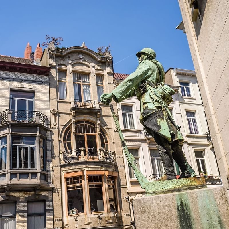 War Memorial statue by an Art Nouveau building with large circular windows near Hotel Barsey by Warwick