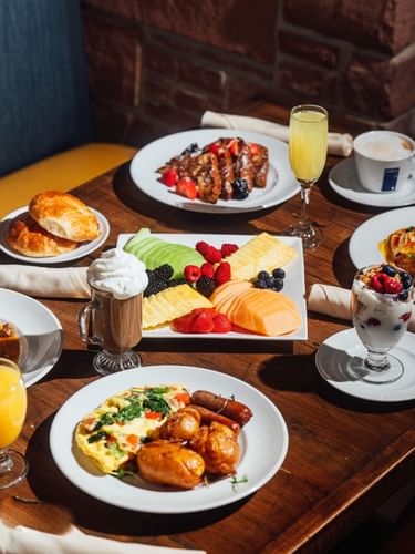 Fresh fruit, pastries, and eggs on a wooden table in In-Room Dining at Warwick Denver