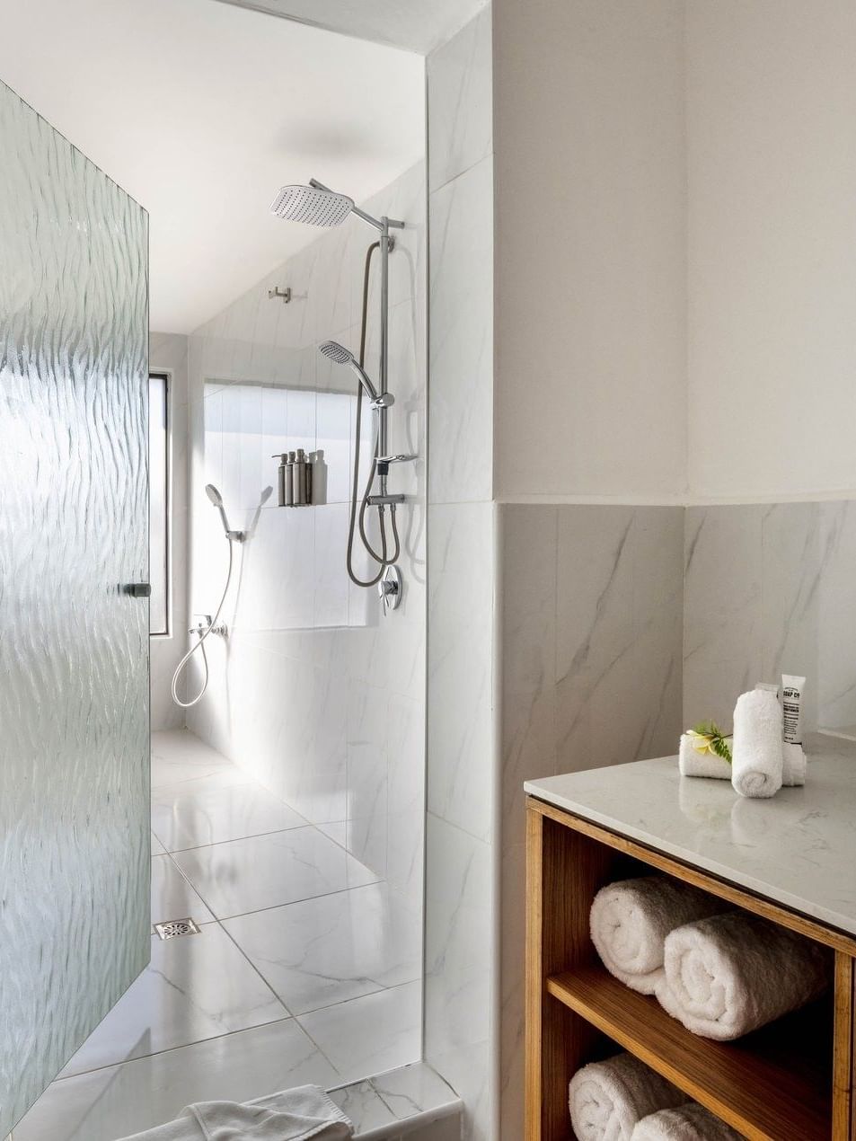 Garden View Room King bathroom with a white marble walk-in shower and a stylish wood vanity unit at warwick le lagon-vanuatu