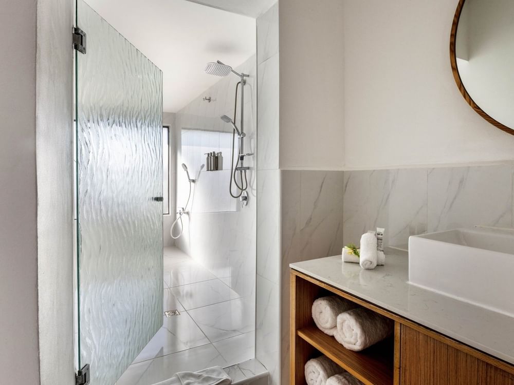 Garden View Room King bathroom with a white marble walk-in shower and a stylish wood vanity unit at warwick le lagon-vanuatu