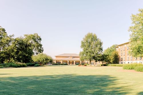 green field with college buildings in background