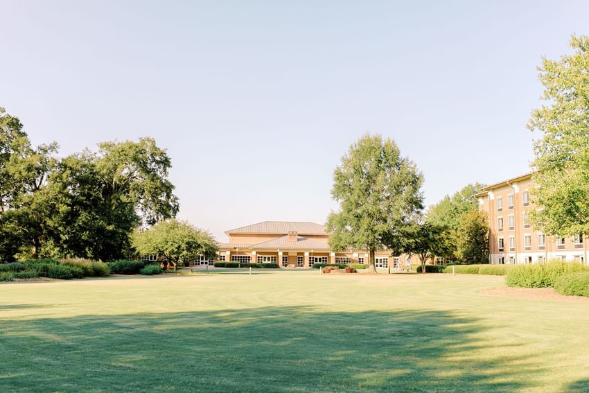Lakeside grounds and scenic exterior view featuring green lawn and tall trees at Clemson University Conference Center & Inn