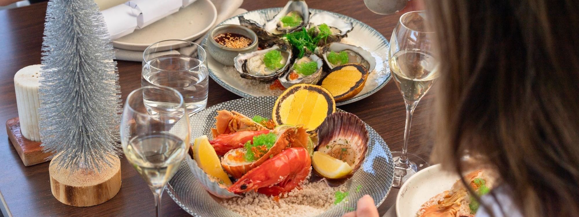 Elegant seafood platter with lobster, oysters, and scallops served with white wine for Christmas Day Lunch.