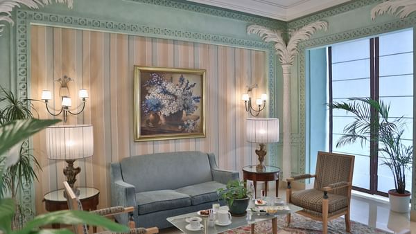 Blue sofa by round glass tables under lamps and a floral painting in the lobby at the Warwick Palm Beach Hotel