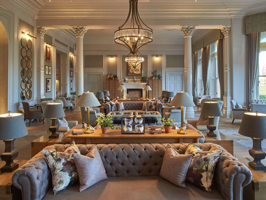 Elegant lounge with tufted sofas, columns and a large chandelier illuminating the comfortable seating at The Milner York
