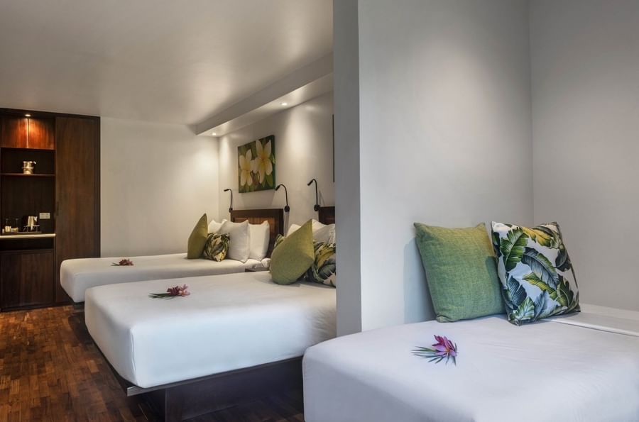 Three beds with leaf pillows and a wall painting by a partition in Superior Garden View Rooms at Warwick Fiji Resort and Spa