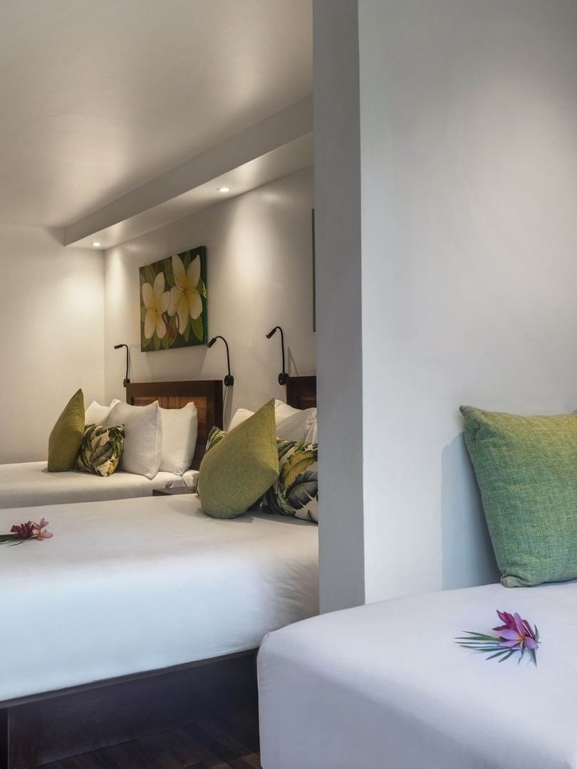 Three beds with floral pillows in Superior Garden View Rooms by a white wall at Warwick Fiji Resort and Spa