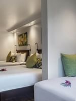 Three beds with floral pillows in Superior Garden View Rooms by a white wall at Warwick Fiji Resort and Spa