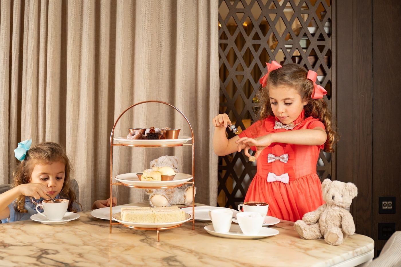 Two young girls having tea with desserts at The May Fair Hotel, London.