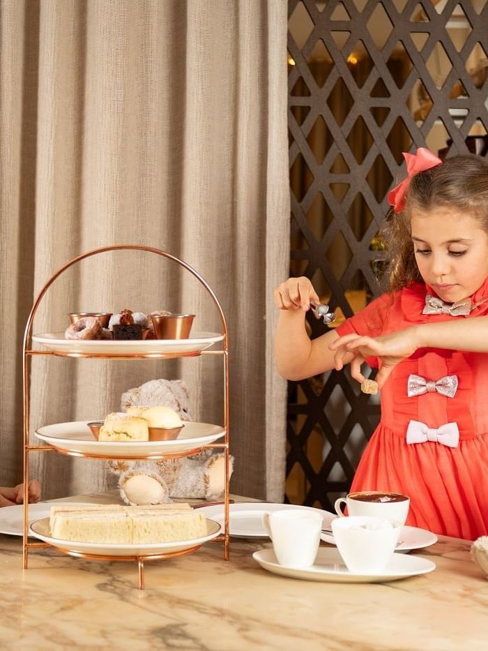 Two young girls having tea with desserts at The May Fair Hotel, London.