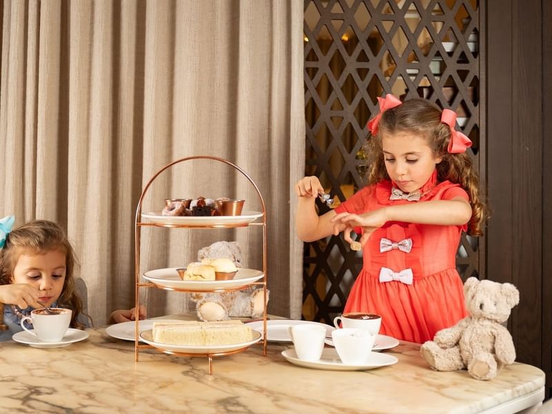 Two young girls having tea with desserts at The May Fair Hotel, London.