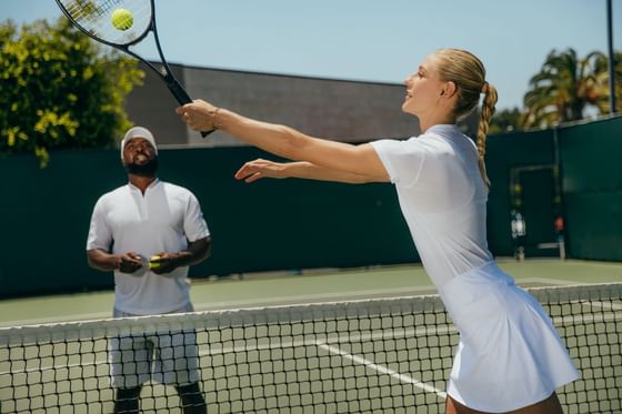 People practicing tennis in the court at Luxe Sunset Boulevard Hotel