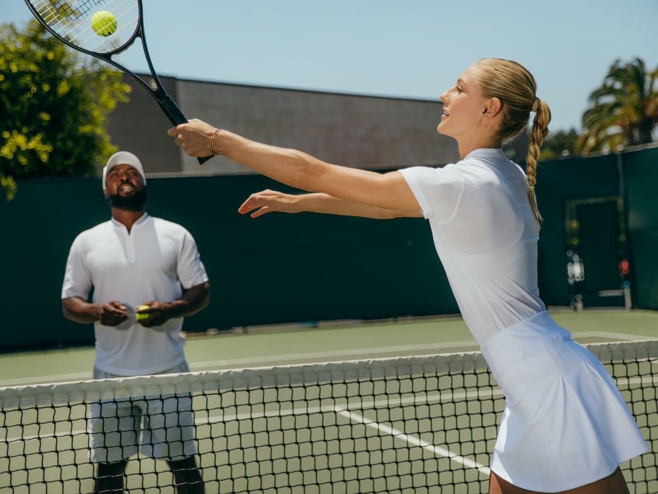 Guy and girl playing tennis on Wilson court