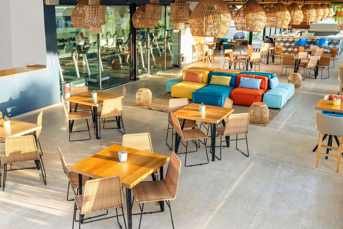 Terraza Roof Garden con sillas de mimbre, sofás coloridos y lámparas colgantes en Fiesta Inn