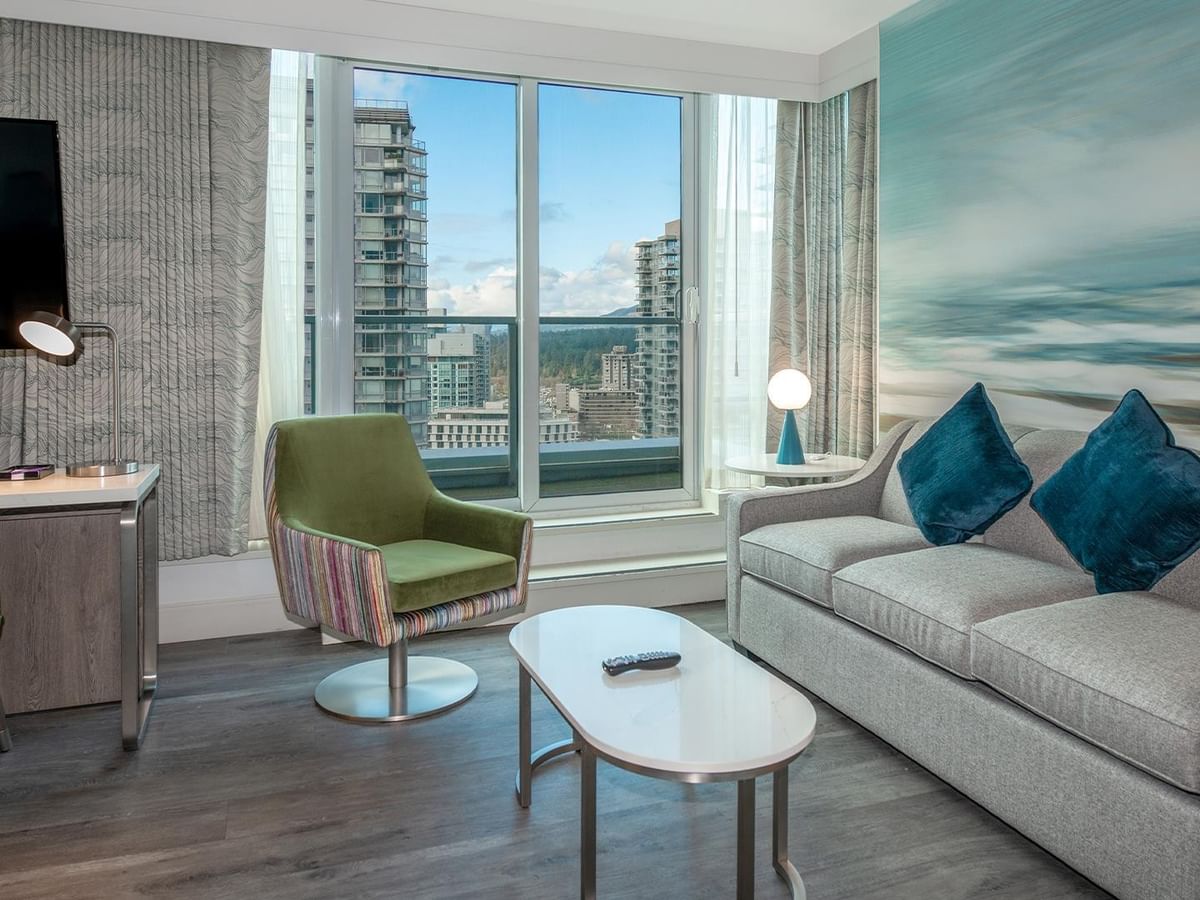 Living area of hotel room with couch, chairs, and balcony.