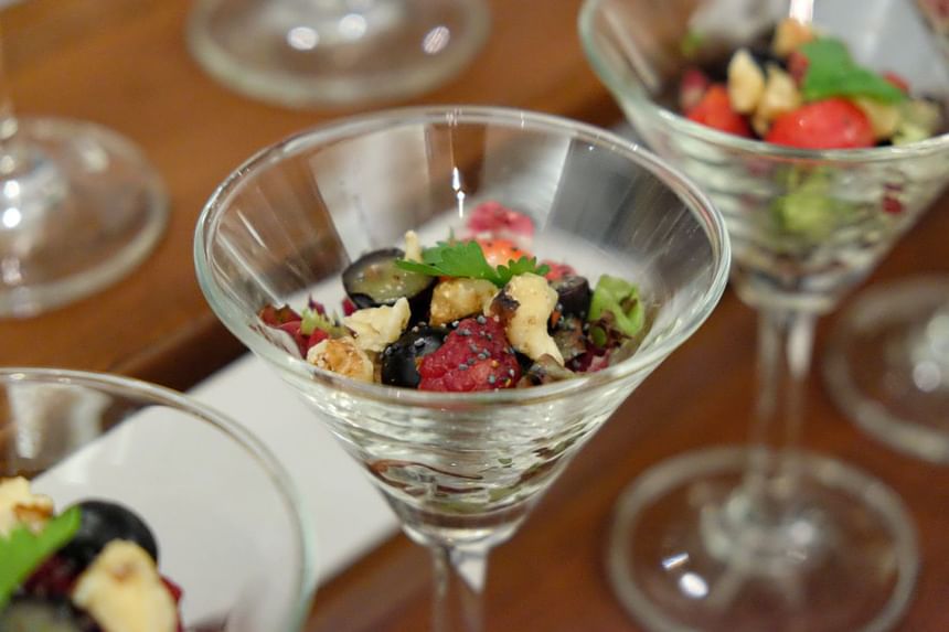 Glass dessert cup filled with vibrant mixed fruit topped with nuts and herbs at Park Hyatt Saigon