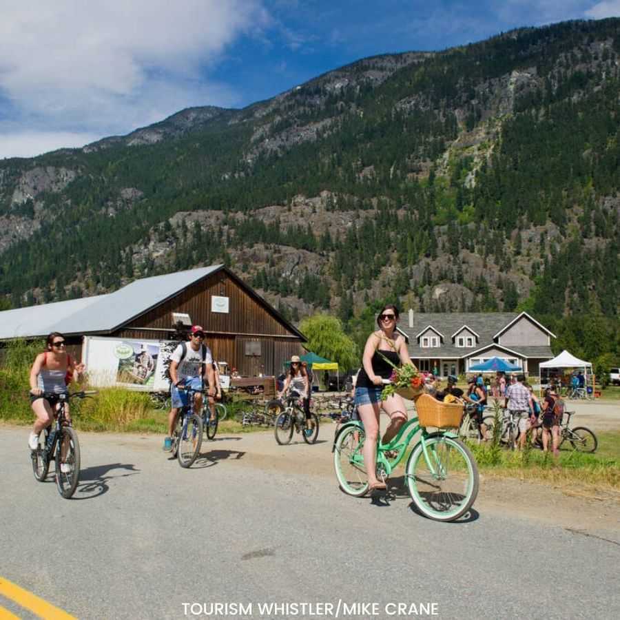 People cycling on the street with mountain backdrop near Blackcomb Springs Suites