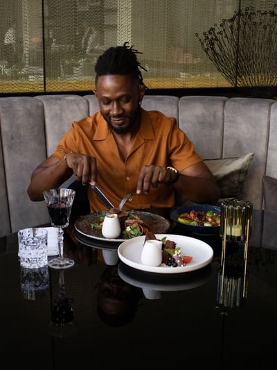 Man dining in a restaurant with a meal and drinks served on a table at Sofitel Brisbane Central