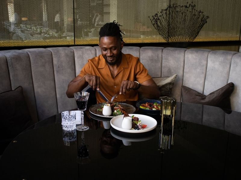 Man dining in a restaurant with a meal and drinks served on a table at Sofitel Brisbane Central