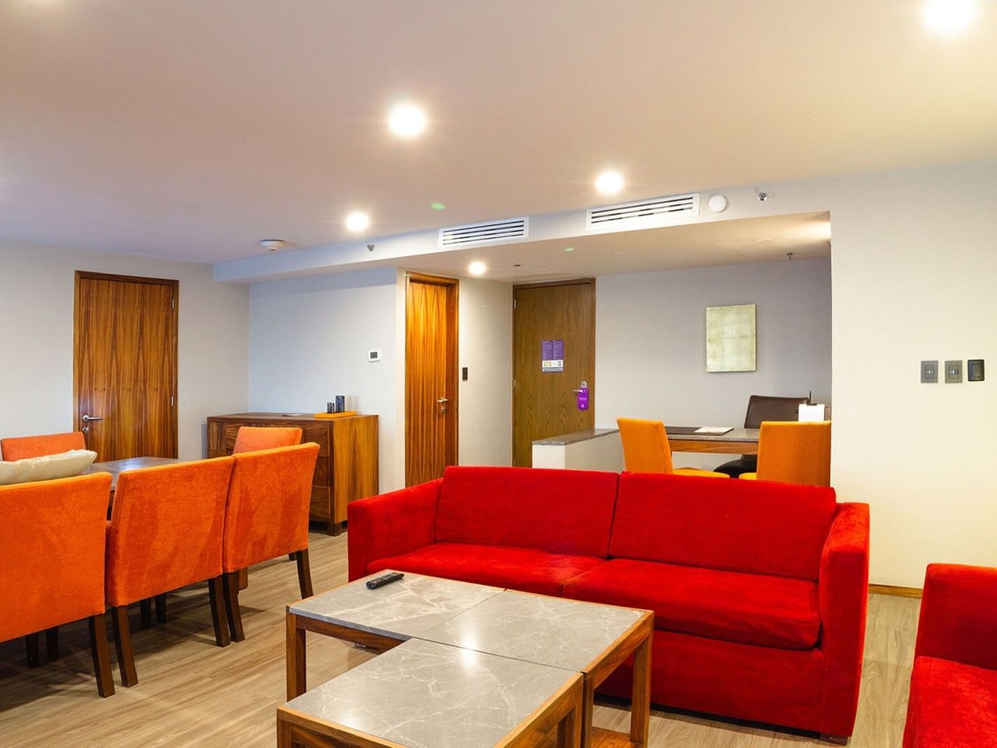 Sala de estar de la Master Suite King con sofás rojos y mesas en Camino Real Aeropuerto México, Ciudad de México.