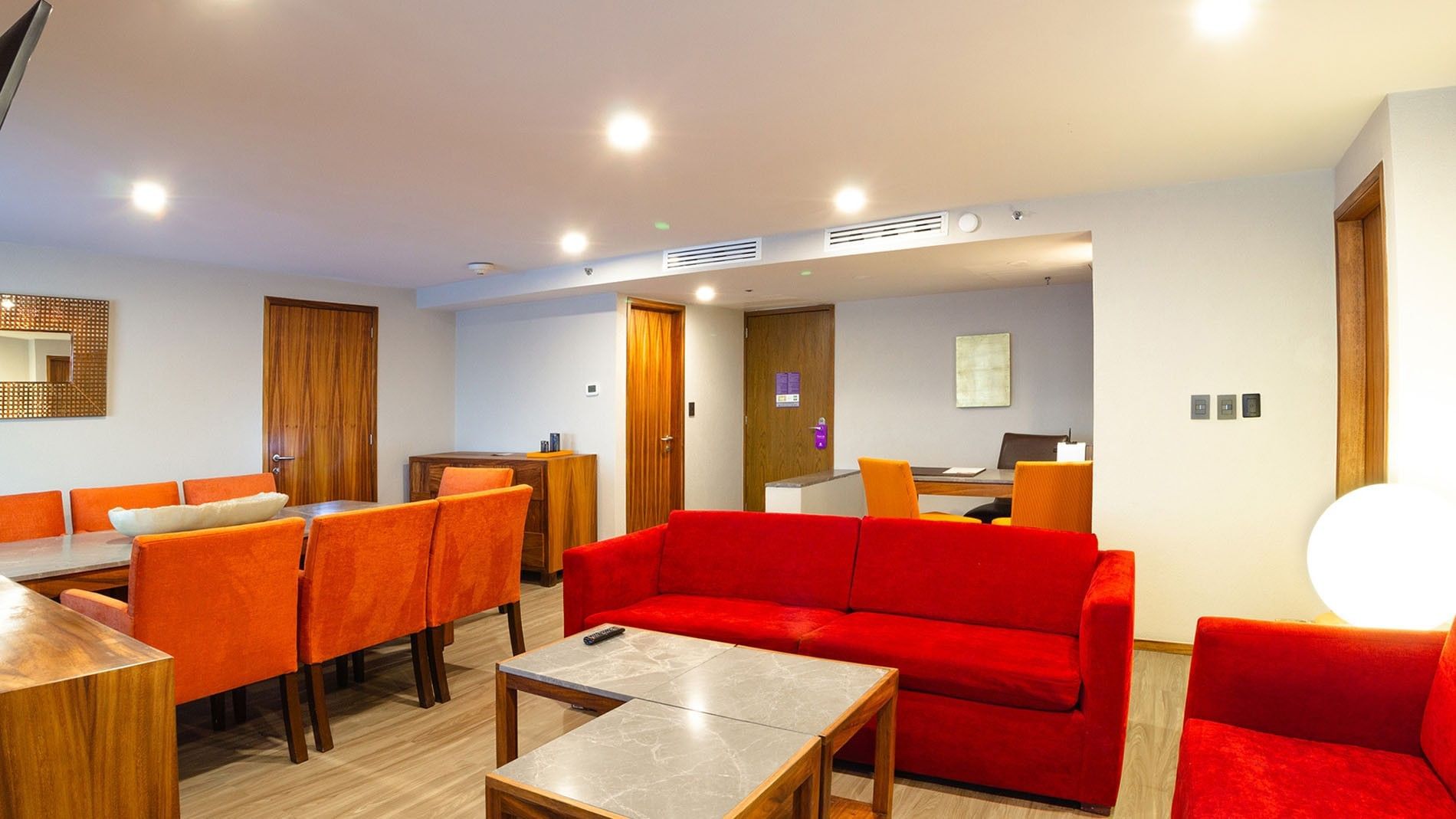 Sala de estar de la Master Suite King con sofás rojos y mesas en Camino Real Aeropuerto México, Ciudad de México.