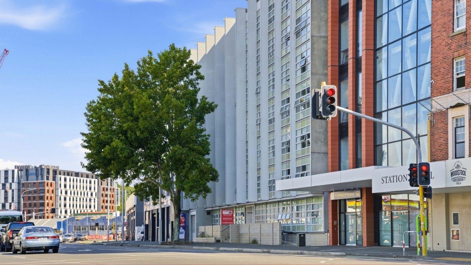 Traffic and buildings on a city street with Student Living Auckland Anzac in view.