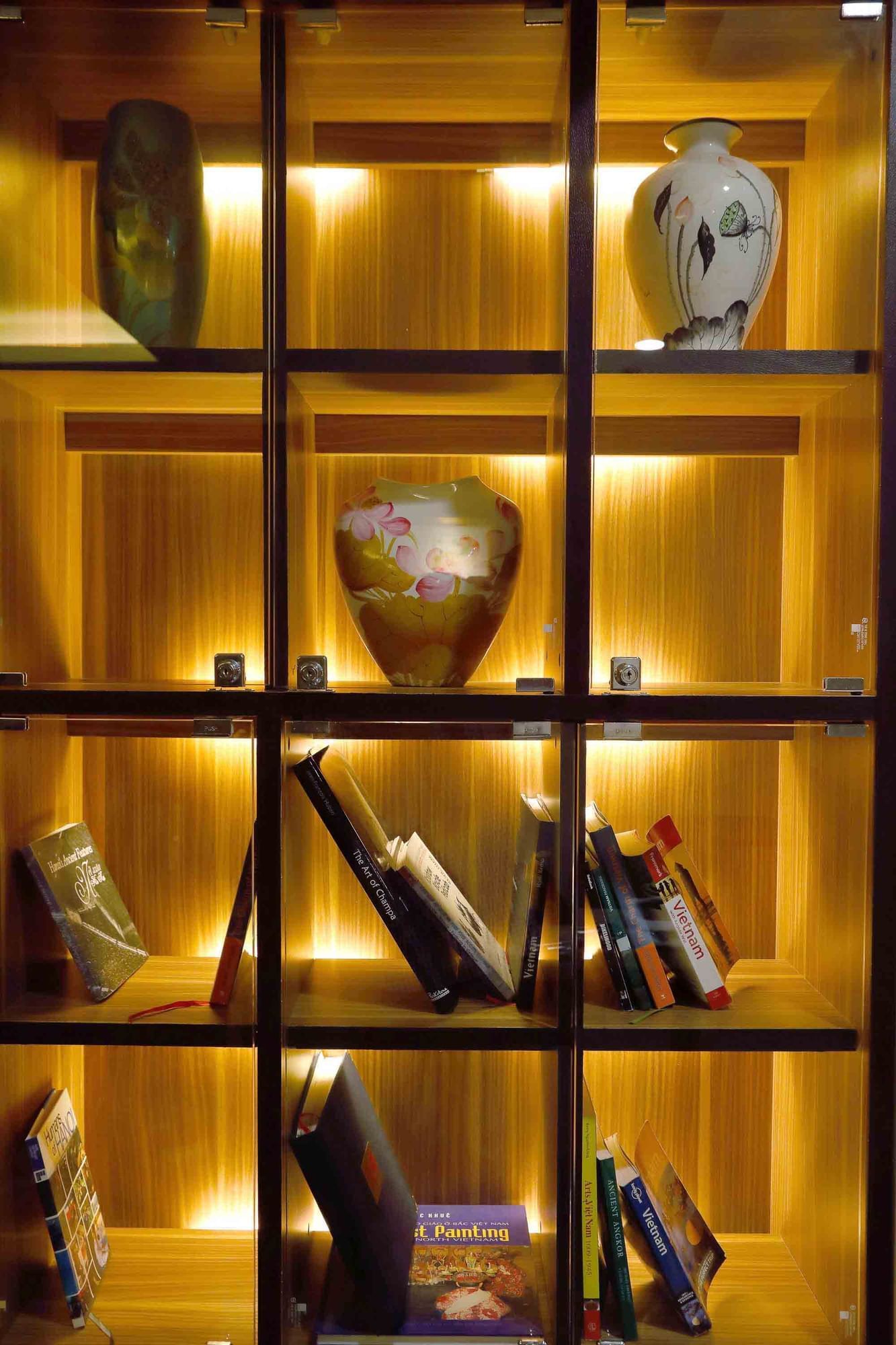 Illuminated wooden bookshelf with decorative vases & books at Sunway Hotel Hanoi